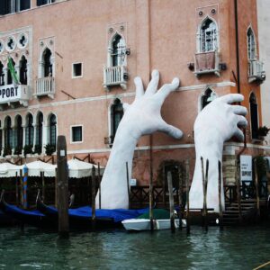 Scultura che sostiene un palazzo a Venezia che sta affondando a causa del cambiamento climatico